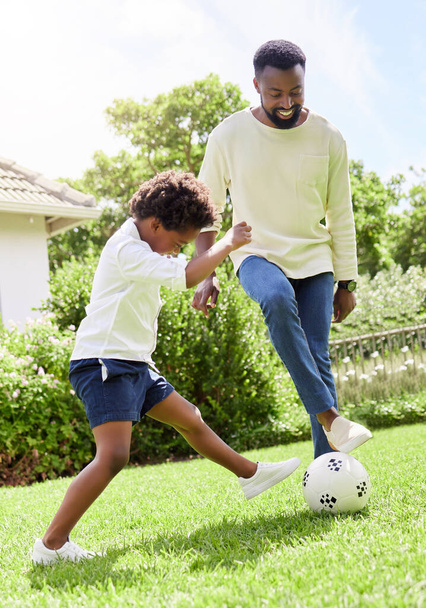 a father and son playing soccer together outdoors. - Фото, изображение