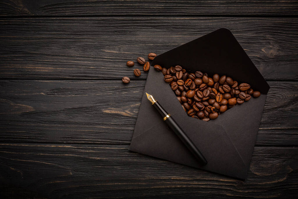 Coffee beans on a kraft paper envelope. Black background. High quality photo - Zdjęcie, obraz