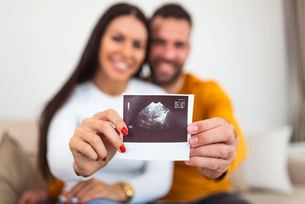 Woman and her boyfriend holding up an image of her sonogram of the baby. Young happy Couple with baby ultrasound photo - Foto, Imagem