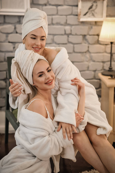 beautiful young woman with towel on her head in bathrobe and smiling at camera - Foto, imagen