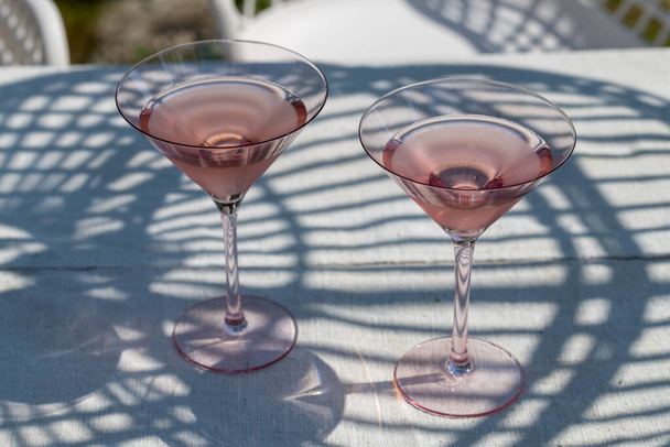 Two glasses with cold pink rose on a garden table in the summer sun. High quality photo - Valokuva, kuva