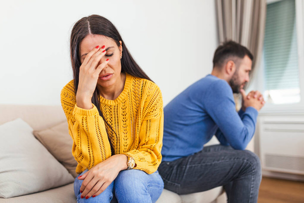 Married couple sitting together not looking at each other on couch in living room at home after quarrel. Angry husband frustrated wife. Break up, problems trouble in relationship concept - Photo, image