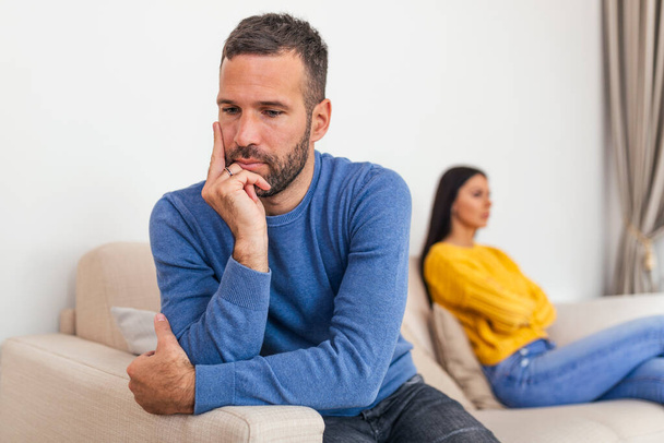 Young couple sitting on sofa being angry after fight. Couple Having Argument At Home. Girlfriend and boyfriend sitting next to each other angry, couple fighting - Foto, imagen