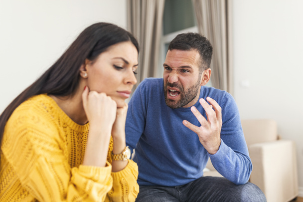 Young sad afraid woman and her violent screaming man. Young couple fighting at home, boyfriend shouting at girlfriend. Stressed out couple having problems. Divorce concept. - Fotoğraf, Görsel