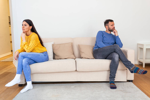 Mąż i żona siedzą na kanapie i nie rozmawiają po kłótni w domu. Koncepcja dystansu społecznego - Zdjęcie, obraz