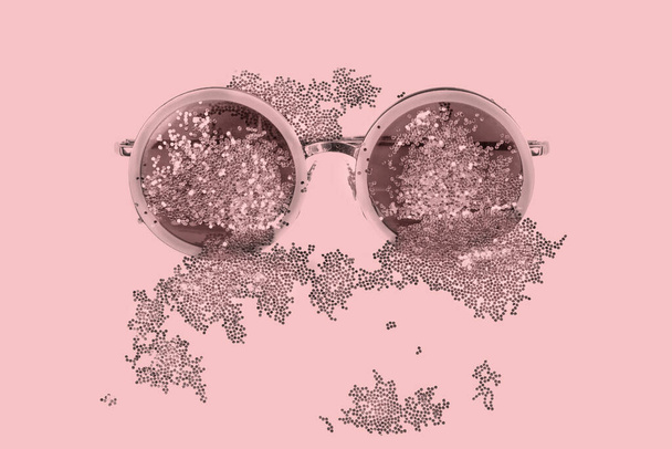 Pink sunglasses with sparkles on a pink background. - Photo, Image