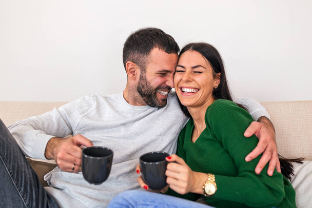 Happy Couple Spending Time Together Drinking Tea And Talking Sitting On Sofa At Home. Shot of a happy young couple relaxing together at home - Φωτογραφία, εικόνα