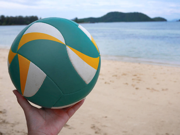 Una mano sosteniendo Voleibol Playa con fondo de playa - Foto, Imagen