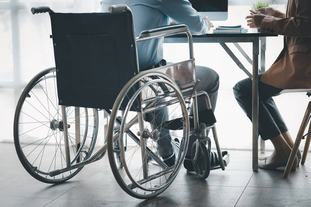 Człowiek siedzi na wózku inwalidzkim i burzy mózgów z kolegami, prowadzi interesy, rekrutuje osoby niepełnosprawne do pracy, pracuje z zespołami wewnętrznymi i ma osoby niepełnosprawne jako część zespołu. - Zdjęcie, obraz