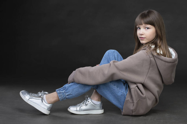 Girl in a sweatshirt and jeans on a gray background. beautiful teen girl. - Foto, Imagen