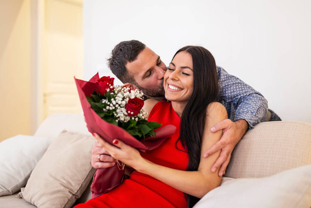 Krásný, šťastný, pozitivní pár objímající, držící kytici rudých růží, 14. února Šťastný Valentýn. Hezký muž dává květiny své přítelkyni, romantické šťastné páry na Valentýna - Fotografie, Obrázek