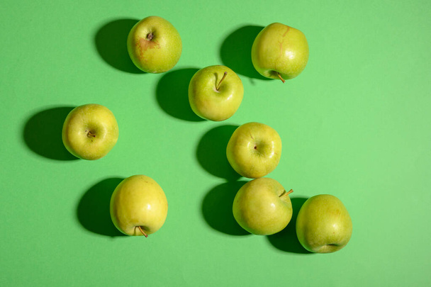Still life photo of fresh green ripe apples on a green background. Still life food photography for many purposes - 写真・画像