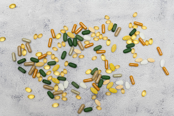 Various medicine pills scattered all over a rustic table. Many different colors, shapes and sizes. Perfect for both topics of abuse and of health - Fotoğraf, Görsel
