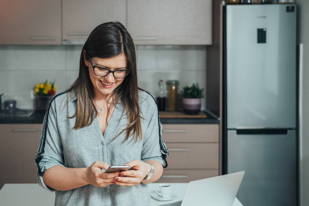 Smiling Businesswoman Using A Mobile Phone At Home - Foto, Bild