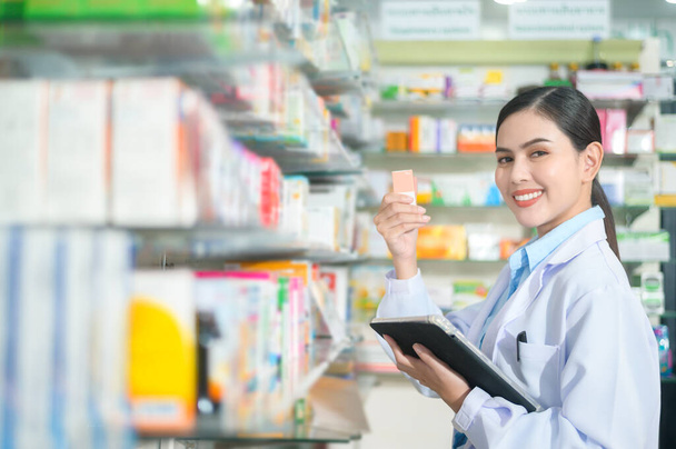A Portrait of female pharmacist using tablet in a modern pharmacy drugstore. - Valokuva, kuva