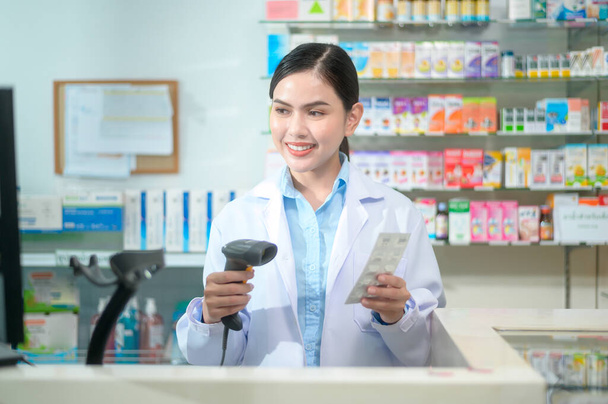 A Female pharmacist scanning barcode on a medicine box in a modern pharmacy drugstore. - 写真・画像
