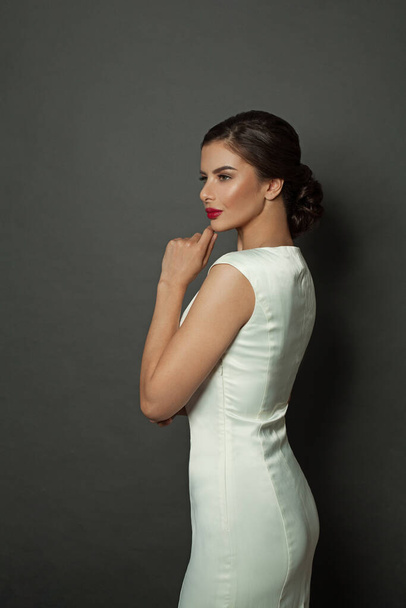Beautiful stylish woman fashion model wearing white dress standing on black background - Zdjęcie, obraz