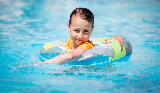 Portrait of happy kid have fun in the pool. Joyful child girl on inflatable ring. Travel, healthy lifestyle, swimming activities and summer holiday concept.  - Foto, imagen