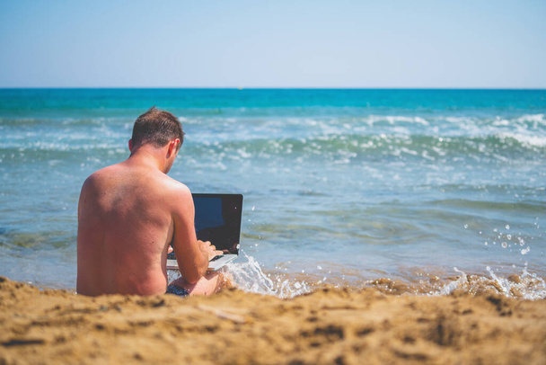 Back view of businessman working remotely with laptop. Copy space. - Zdjęcie, obraz