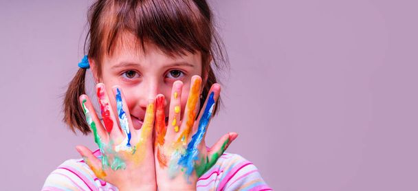 Portrait of happy little cute child girl with colorful painted hands as symbol of happiness and joyful life. Copy space. - Fotografie, Obrázek