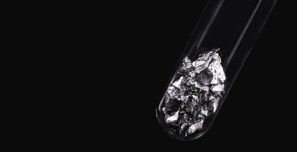 Chromium fragments inside test tube, industrial use ore, metallic chemical element, isolated on black background - Φωτογραφία, εικόνα