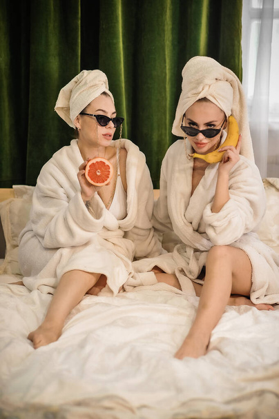 dwie kobiety w szlafrokach i szlafroku z ręcznikiem i ręcznikami na twarzy w spa - Zdjęcie, obraz
