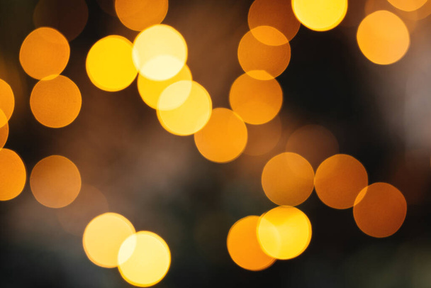 Defocused bright abstract holiday background with yellow and orange twinkling sunspots. Bokeh Copy space for text. Merry Christmas and Happy New Year - Photo, Image