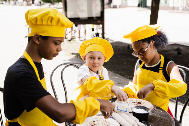 Childhood cook activity of multinational children of black african and caucasian kids. Happy company of multiethnic children cooking dough - Photo, image