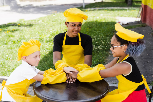 Multiracial children cook touching hands together forming pile. Friendship of multinational kids. Childhood. cooks in chefs hat and yellow apron uniform put hands on each other - Φωτογραφία, εικόνα