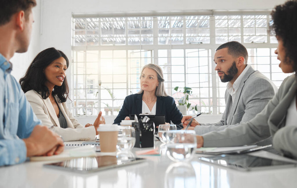 Group of five diverse businesspeople talking in a meeting together at work. Business professionals talking and planning in an office. Young african american businesswoman discussing an idea with - Zdjęcie, obraz