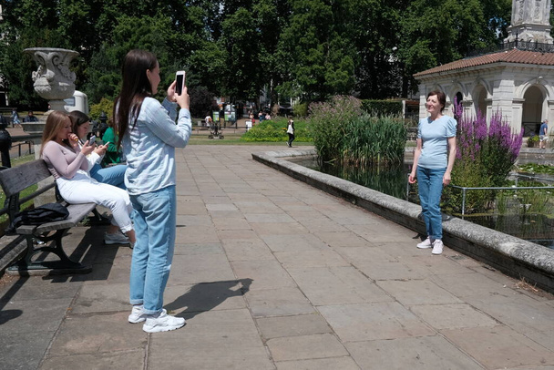 People take photos in a city centre park on July 7, 2022 in London, UK. - Foto, afbeelding