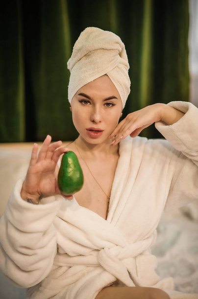 gyönyörű fiatal nő zöld szemekkel és törölköző a fején egy fehér fürdőköpeny - Fotó, kép