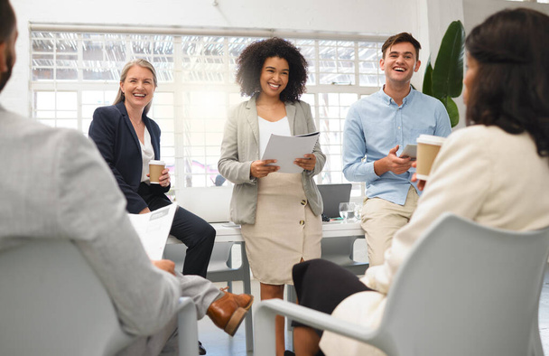 Group of five diverse businesspeople having a meeting in an office at work. Cheerful coworkers laughing together in a workshop. Business professionals planning and going through a report. - Φωτογραφία, εικόνα