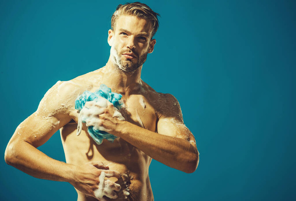 Sexy macho taking shower. Bearded hipster is washing body with sponge. Skin care, spa, beauty - Fotoğraf, Görsel