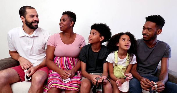 interraciale familie en kinderen samen lachen op zoek naar mobiele telefoon thuis sofa - Foto, afbeelding