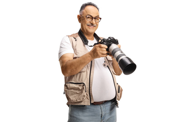 Mature male photo journalist holding a professional camera and smiling at camera isolated on white background - Fotografie, Obrázek