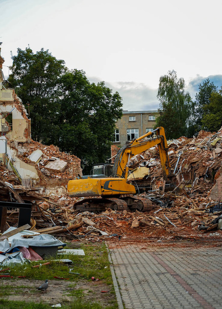 Bulldozer, a type of construction machine with a hydraulically operated shovel on the front and an excavator arm on the back destroying a house apartment building. - Foto, Bild