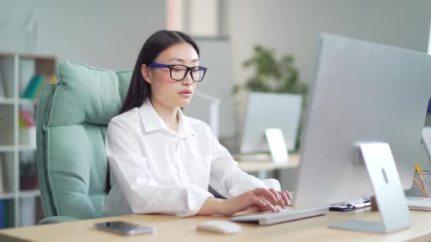 Young Asian woman worker, employee entrepreneur with stomach pain, poisoning, Premenstrual syndrome, heaviness in abdominal Suffering sitting at workplace at work in office at computer desk. Indoor - Felvétel, videó