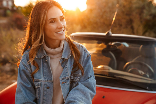 White ginger woman smiling while standing by car outdoors - Foto, Bild