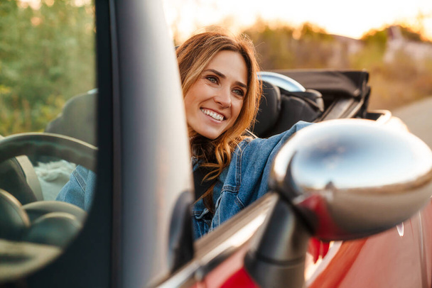 White ginger woman smiling while driving car during trip - Fotó, kép