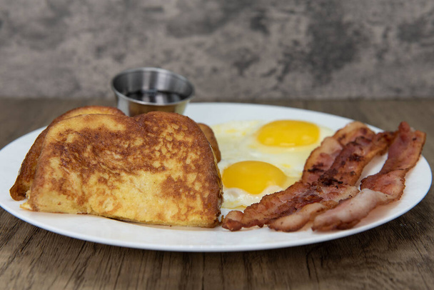 Traditional American breakfast consisting of french toast, fried eggs, and bacon will ensure that the belly will be full. - Photo, Image