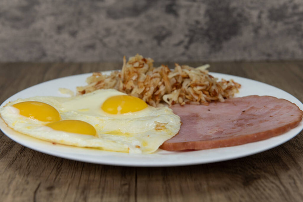 Standard American breakfast consisting of ham, fried eggs, and hash browns will ensure that the belly will be full. - Photo, Image
