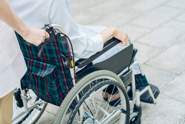 Kobieta na wózku inwalidzkim i kobieta w fartuchu do opieki na świeżym powietrzu - Zdjęcie, obraz