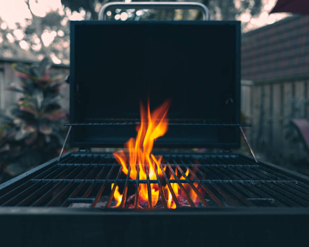 Grill. Flame in a grill. Cook on Backyard. Picnic area with fireplace for barbecue. Professional grill. Fire slow burning. Charcoals grill burning. Photo in dark moody tones. - Photo, image