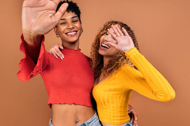 Photo de stock de femmes afro joyeux posant en studio tourné sur fond brun. - Photo, image