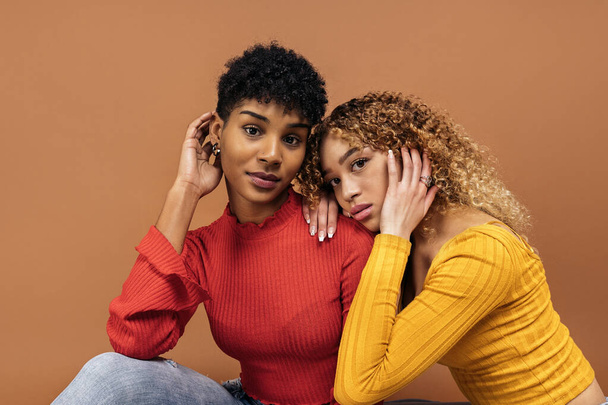 Stock photo of beautiful afro women posing in studio shot against brown background. - 写真・画像