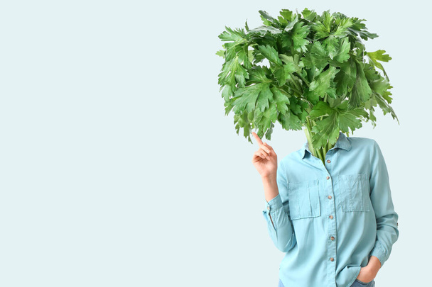 Young woman with fresh parsley instead of her head on light background with space for text - Foto, Imagen