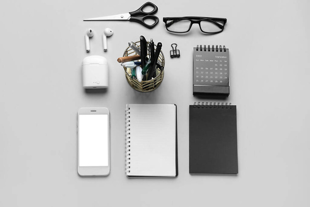 Set de papelería con anteojos, teléfono móvil y auriculares sobre fondo claro - Foto, Imagen