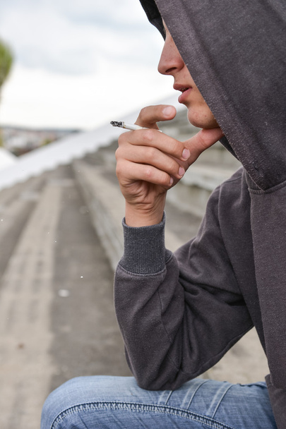 Young man in depression smoking a cigarette on a stadion. Concep - Foto, Bild