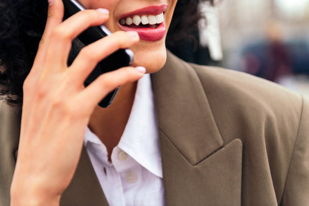 close up of the mouth of a smiling woman talking by mobile phone, concept of communication and urban lifestyle, copy space for text - Foto, Bild
